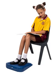 Young student on chair using the tactile foot and support wedge for self- regulation, focus and calm seated movement.