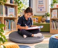 Child using a large tactile cushion for focused learning in a quiet school library.