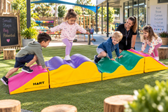 Children using a Sensory Tactile Rollercoaster foam obstacle course in a preschool playground.
