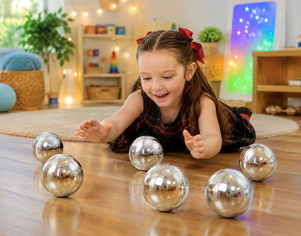 Child exploring reflective TickT Mystery Sensory Balls in a playroom.