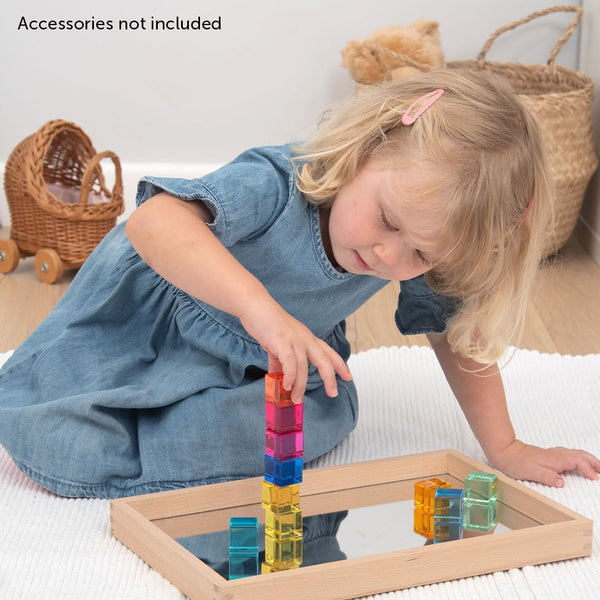 Child stacking colourful TickiT Gem Cubes on a mirror tray.
