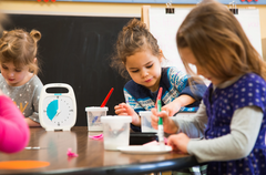 Children at a desk colouring in and using the white and blue coloured Time Timer Original 20 Minutes visual countdown timer with disappearing coloured disk for classroom focus, transitions and time management