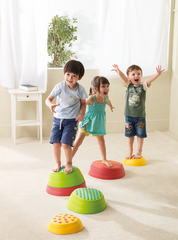 Children balancing on colourful WePlay Rainbow River Stones during a gross motor movement activity