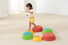Toddler stepping between WePlay Rainbow River Stones during a balance and coordination activity