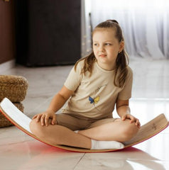 Child sitting and rocking on a Wooden Rocking Balance Board