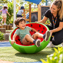 Watermelon Rocking Bowl supporting active sensory play, balance and coordination in an outdoor preschool playground.