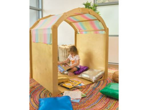 This is an image of a wooden Playhouse Play house. It has a rainbow cover over the top of the arch. It has a child reading books inside. Autism Space - Cosy Retreat
