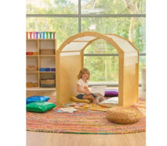 This is an image of a wooden Playhouse Play house. It has a white cover over the top of the arch. It has a child reading books inside. Autism Space - Cosy Retreat