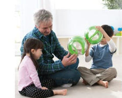 This is an image an adult and 2 children using the Tai-Chi 20 cm balls for sensory overload. The Tai-Chi 20 cm Ball has a clear outer ball with a green inner maze and an orange ball inside.
