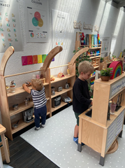 This is an image of the Wooden Interactive Play Stand and Retreat Den that has been opened up and used as shelves. There are two children playing inside.