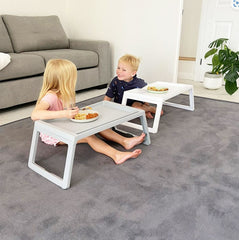 Two children are sitting on the floor using a foldable floor table.