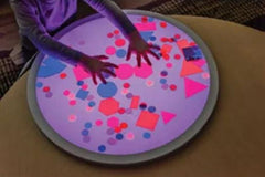 This is an image of the round light panel with hands playing with shapes.