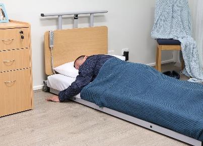 This is an image of a person asleep lying on their stomach with the hospital bed on the floor position