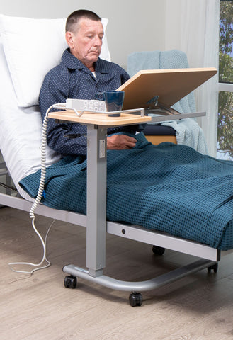 This is an image of a person using an overbed table. It has a split tip top and a rail around it to stop things spilling