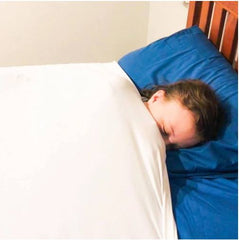 This is an image of a child sleeping under a therapeutic compression sheet to help with  sensory overload