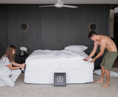 This is an image of 2 people making a bed.