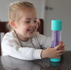 This is an image of a child playing with a blue DIY calm down bottle - good for autism and sensory overload