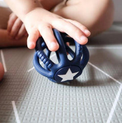 This is an image of a hand rolling the Chewie FIDGET BALL. It is dark blue with a white star