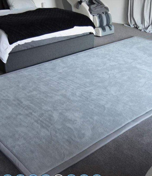 This is an image of the Calming Sensory Touch Mats showing in a light grey, colour. It is in front of a couch